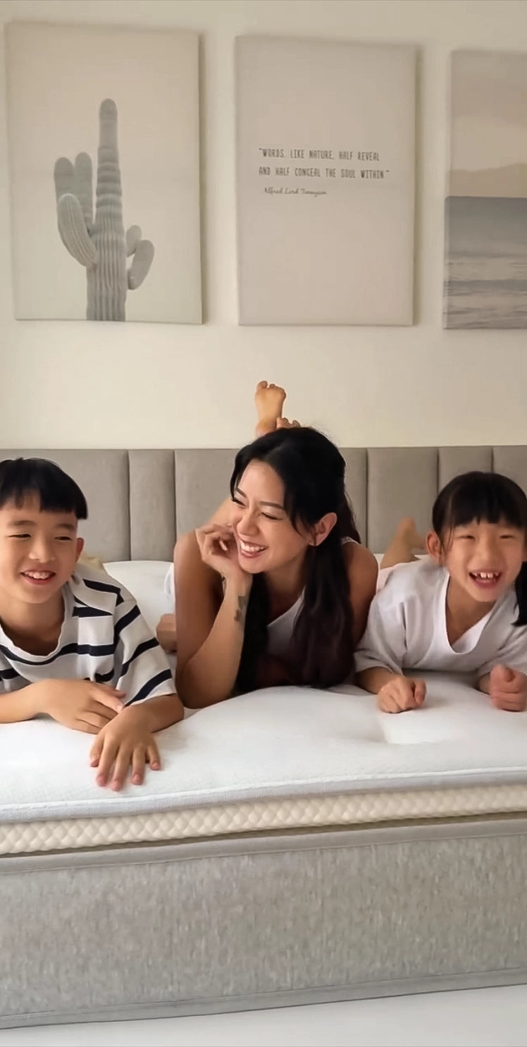 女子與兩名子女一同趴在床上歡笑著