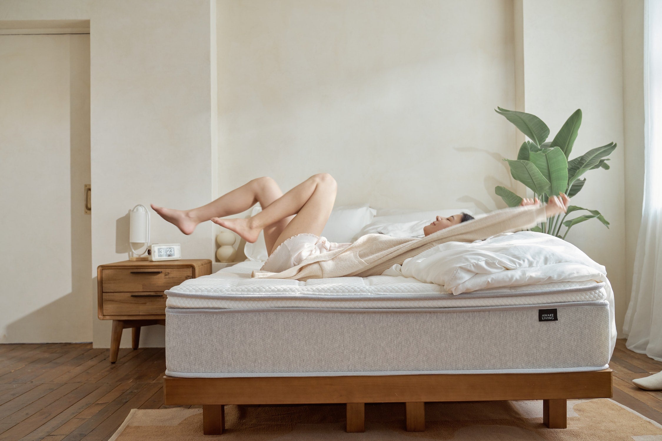 使用者於 Original 2.3 經典好眠床墊上仰躺伸展四肢,畫面呈現厚實床體支撐與天絲表布的柔和觸感,搭配晨光、白色寢具與綠植營造放鬆的早晨氛圍。