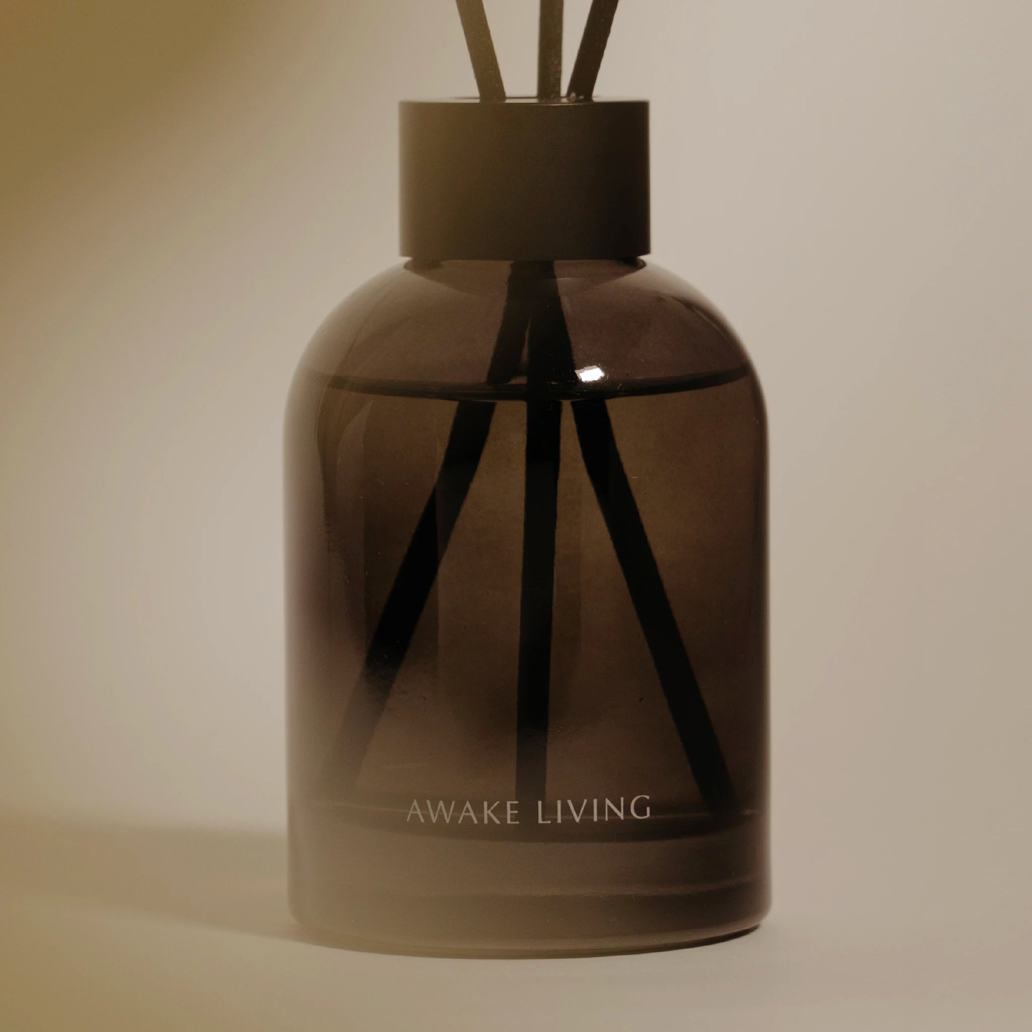 棕色瓶身與黑色瓶蓋中安插著三根擴香棒，瓶身上印製 Awake Living 的字樣。