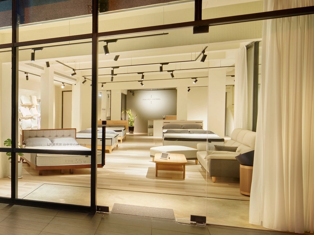 Awake Living 台中文心體驗店門市的夜間全景，可從店外看見內部寬敞明亮的床墊展示區。